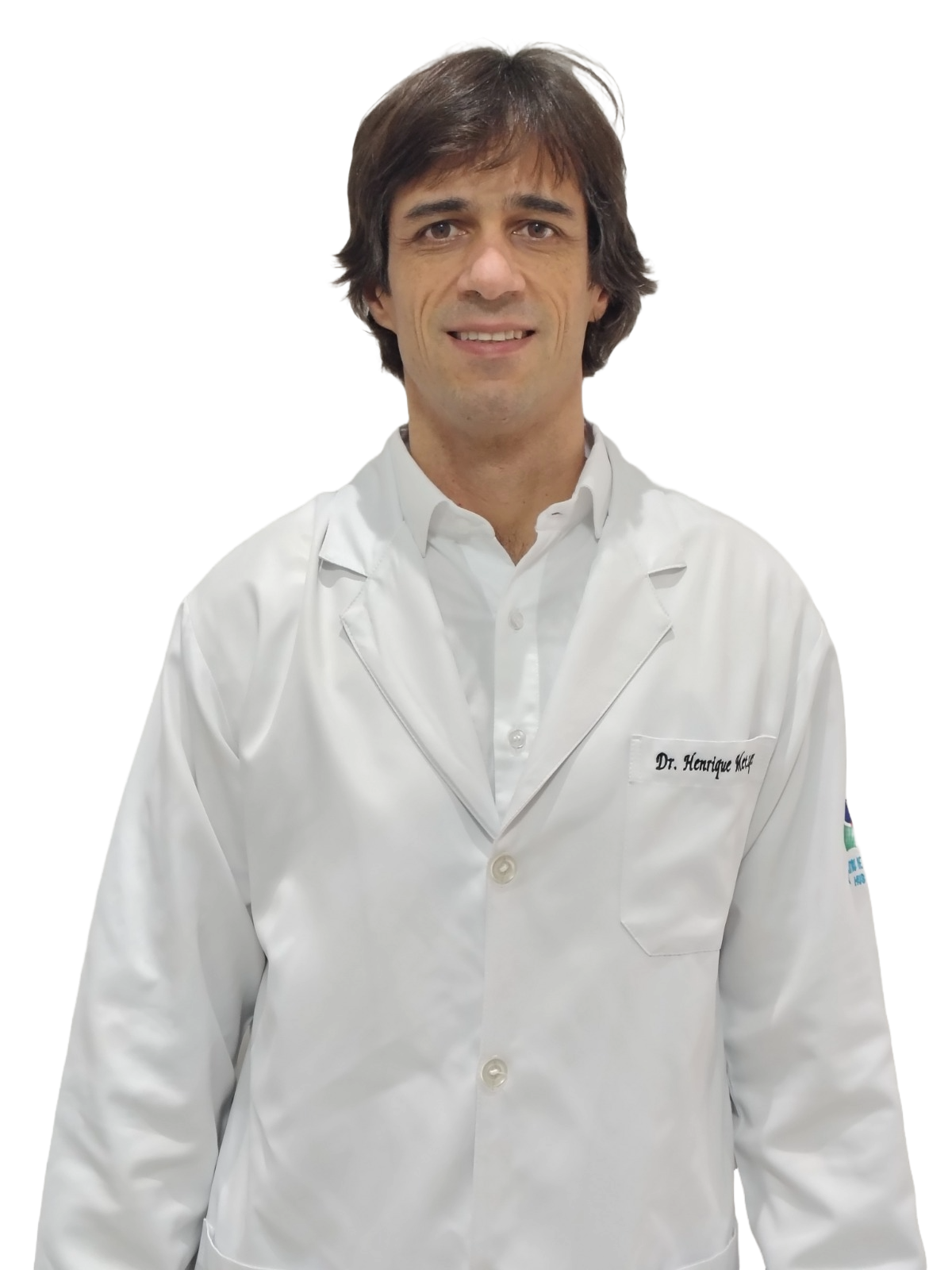 Fotografia de meio corpo do Dr. Henrique Metzger, médico radiologista. Ele é um homem jovem, de cabelos escuros, sorrindo levemente e vestindo uma camisa social clara por baixo de um jaleco branco. O fundo é cinza claro e neutro.